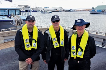 Photo of FRDC staff Crispian Ashby, Patrick Hone and John Wilson wearing safety vests on the water