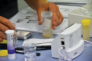 Photo of Casey Nicolas (left) at the recent grower workshop with Scott Singleton (right) preparing an oyster sample for the Noegen tester