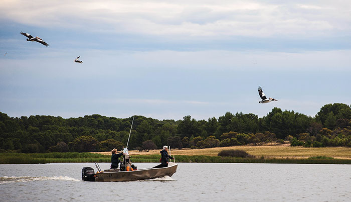 Photo of Gloria Jones and her daughter Christine Jackson in a boat with pelicans flying overhead