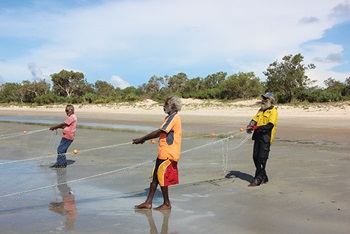 Photo of three men pulling a net in on the beach