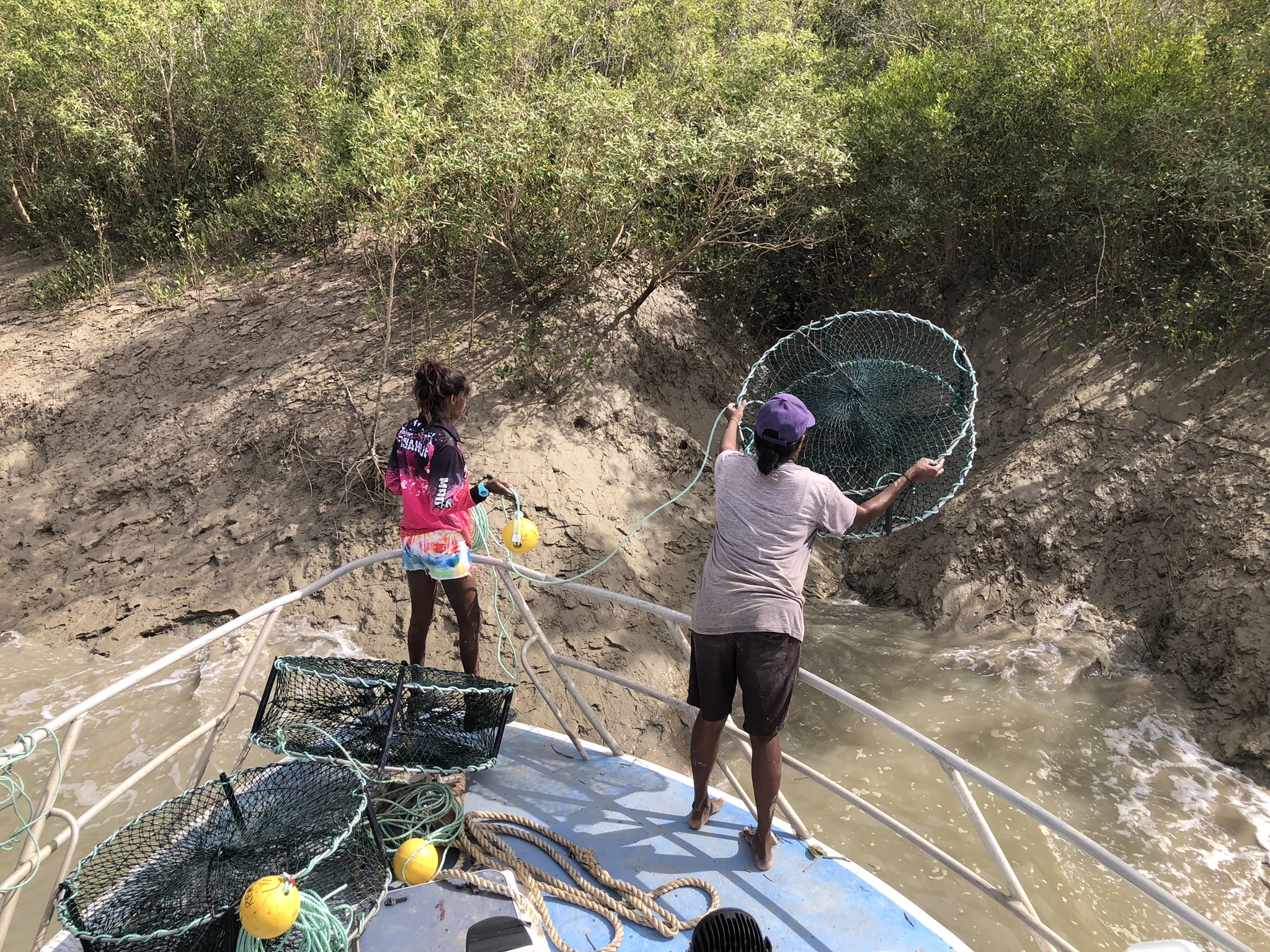 Two Traditional Owners fishing for Mud Crabs off side of boat
