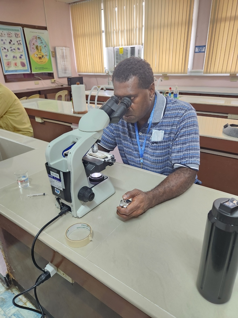 Rocky Stephen looking into a microscope while at his sandfish aquaculture course